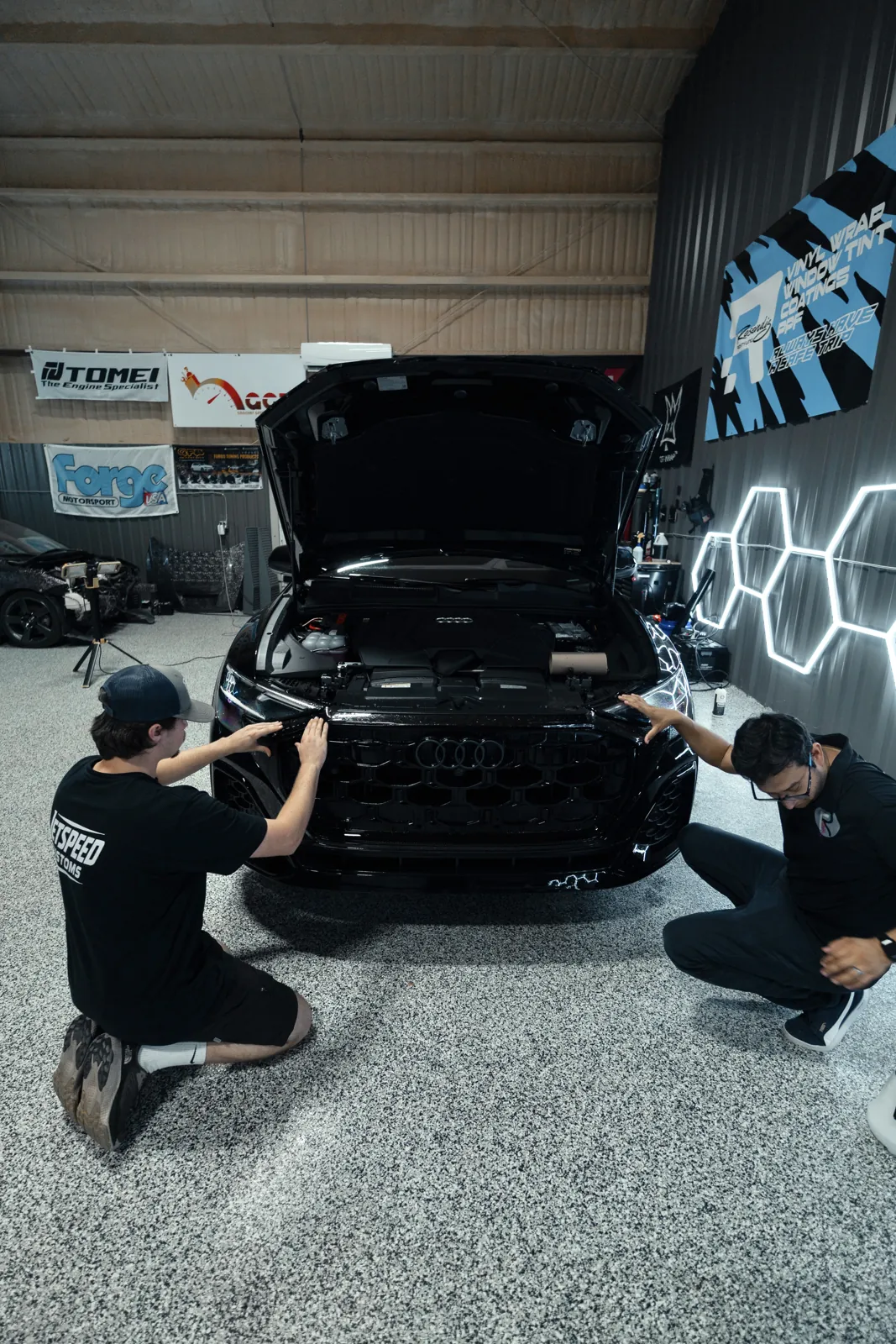Two installers in Resendiz shirts working the front of an Audi Q8, hood open