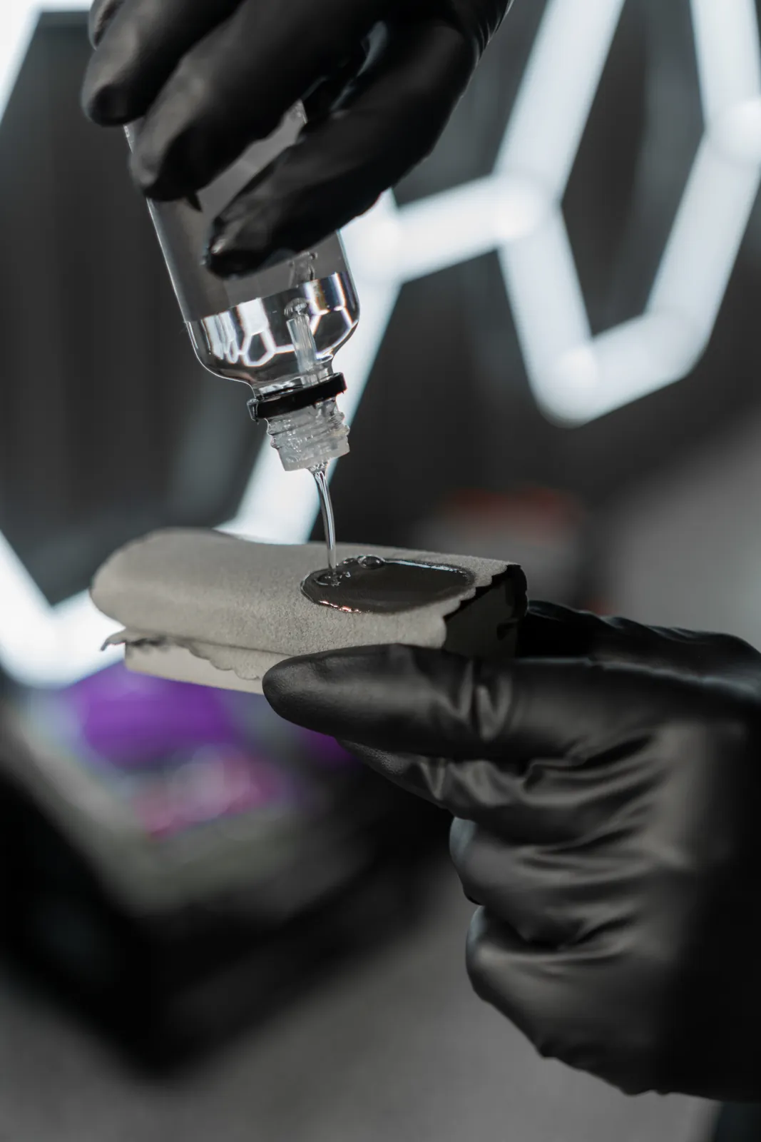 Ceramic coating liquid dropped onto an applicator pad in gloved hands
