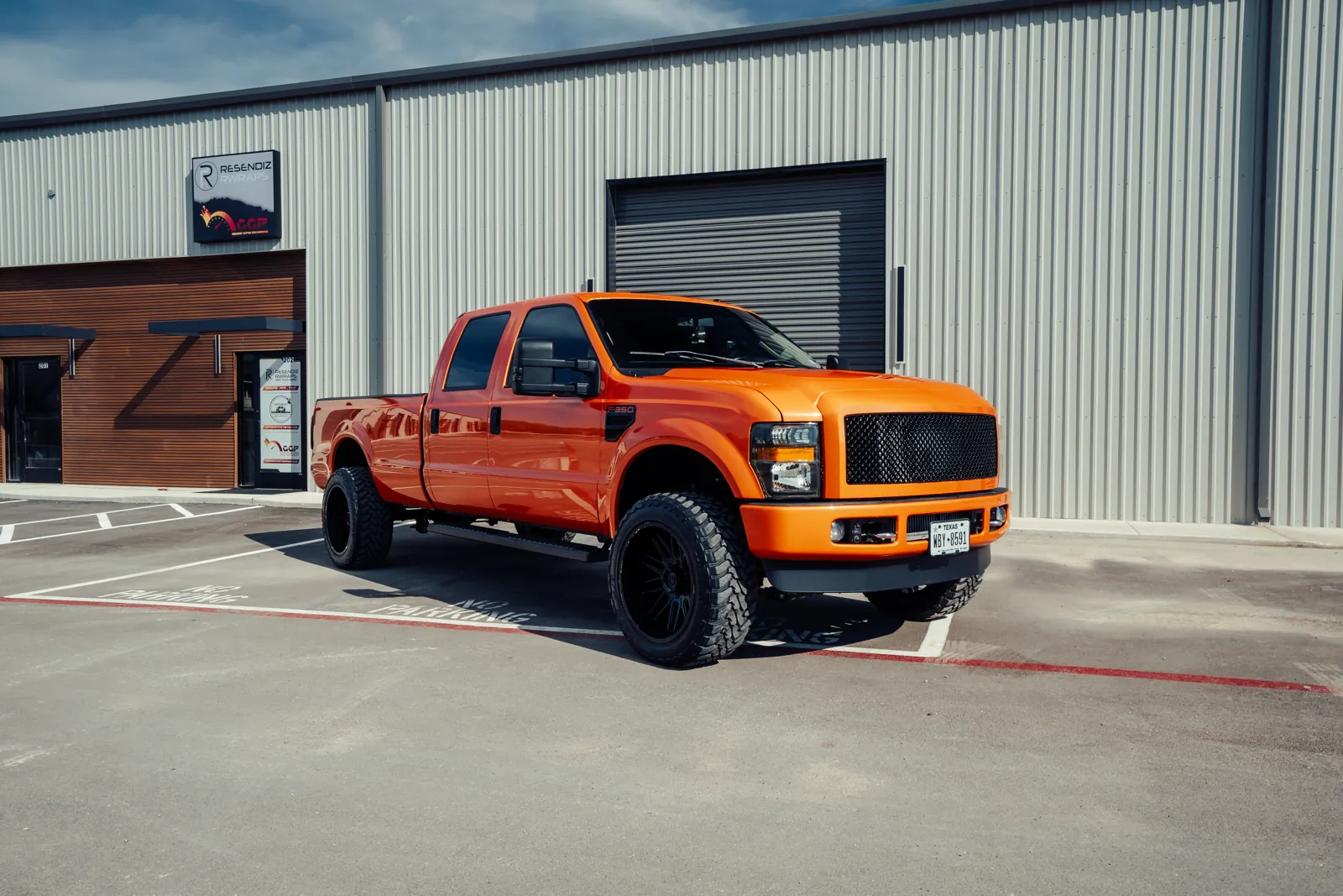 Orange lifted F-350 parked in front of the Resendiz Restyling storefront on Weil Rd