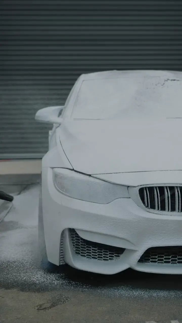 White BMW front end covered in foam during a decontamination wash