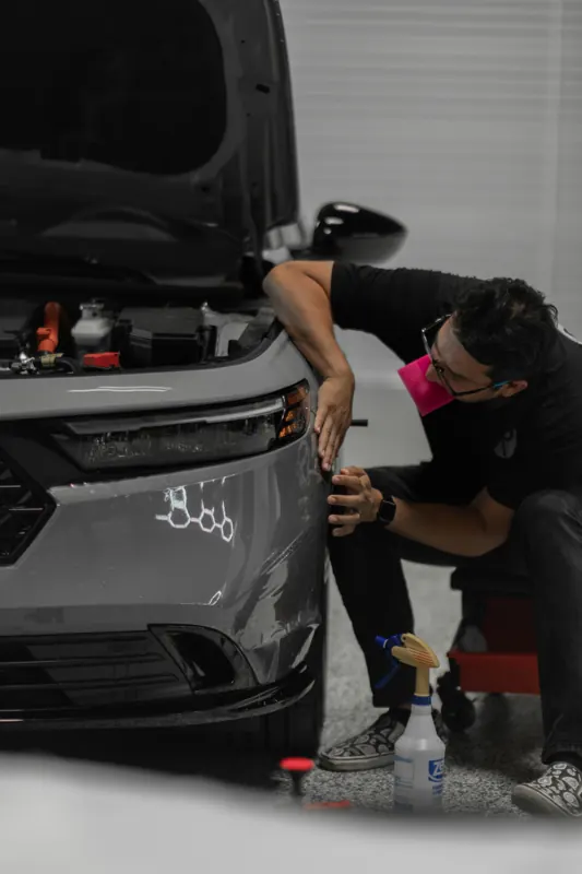 Installer working film into the Accord front corner with a spray bottle