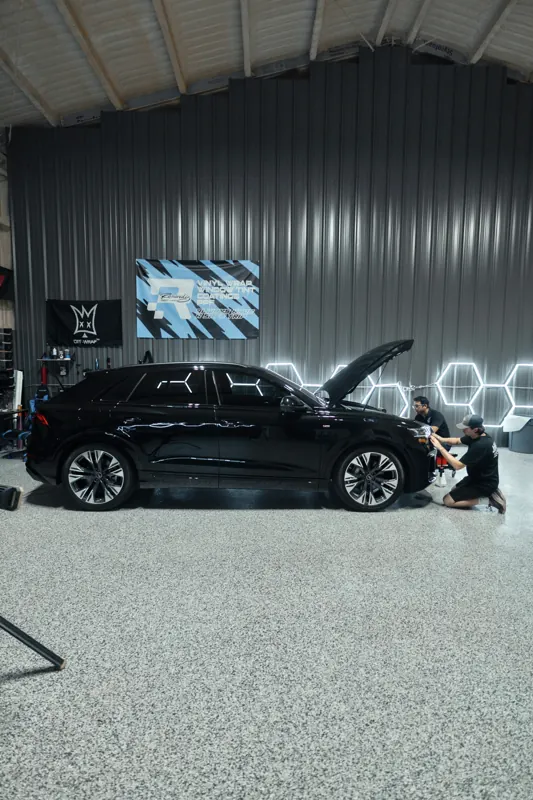 Audi Q8 side view with an installer at the front, banners on the wall
