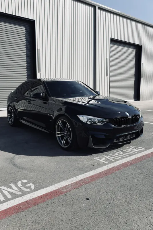 Blacked-out BMW M4 with dark window tint outside the shop bays