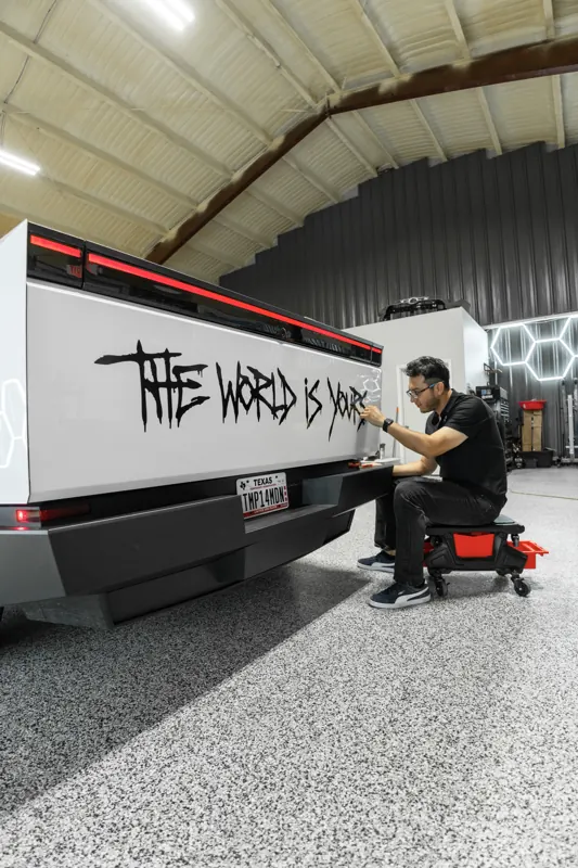 Custom graffiti-style decal being installed on a Cybertruck bed side
