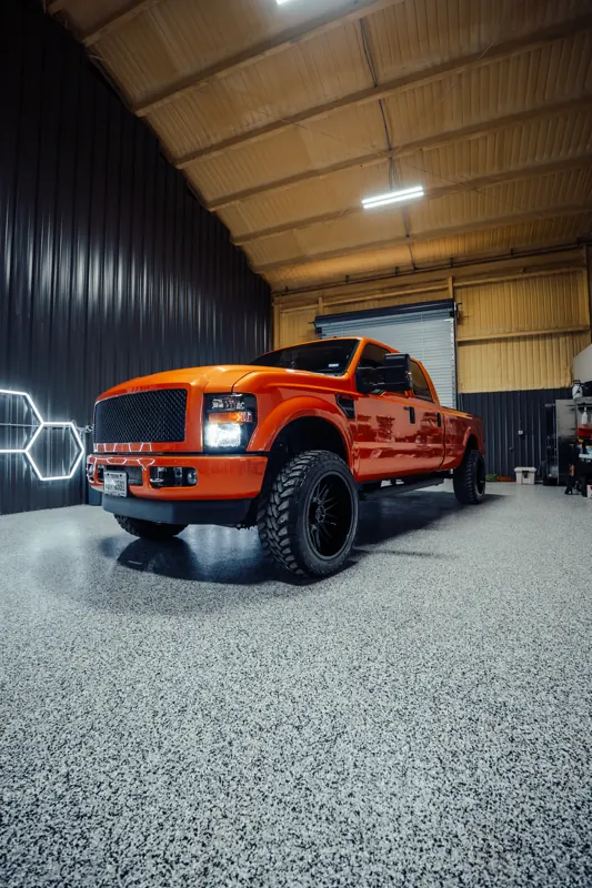 Orange Ford F-350 in the shop under hex lighting