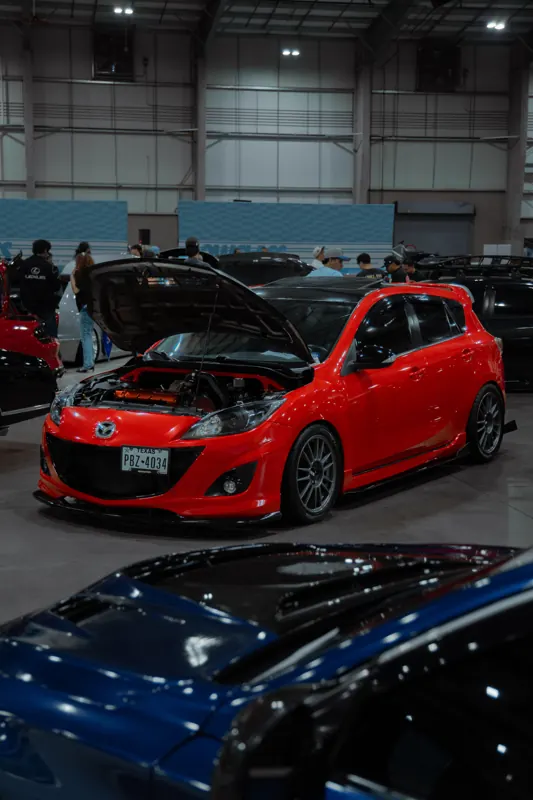 Red Mazdaspeed3 on display at an indoor car show