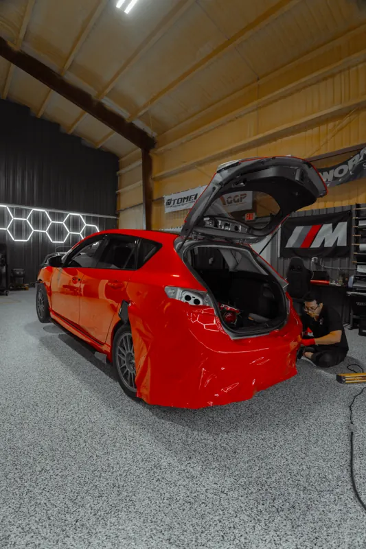 Red Mazdaspeed3 hatchback in the shop, hatch open