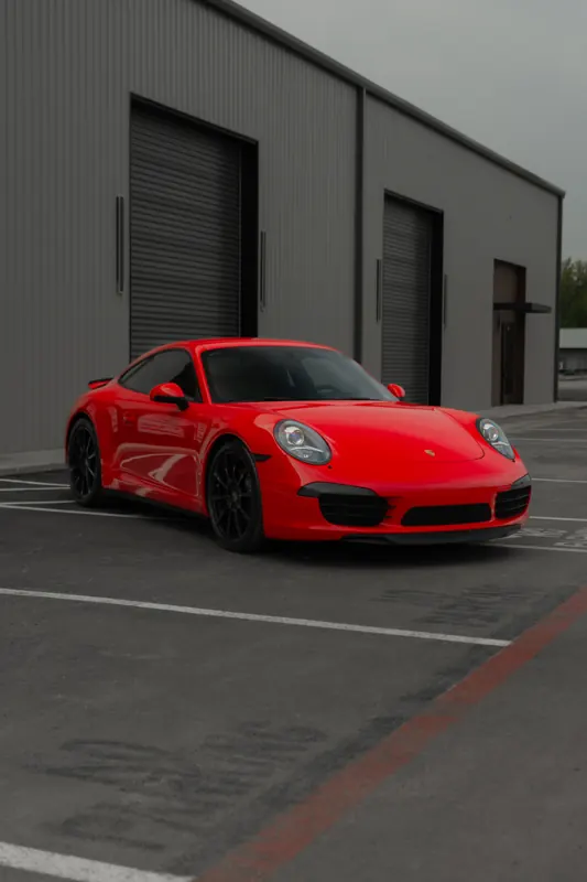 Red-wrapped Porsche 911 parked outside the shop bays