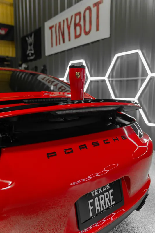 Red Porsche 911 rear with Texas plate inside the shop