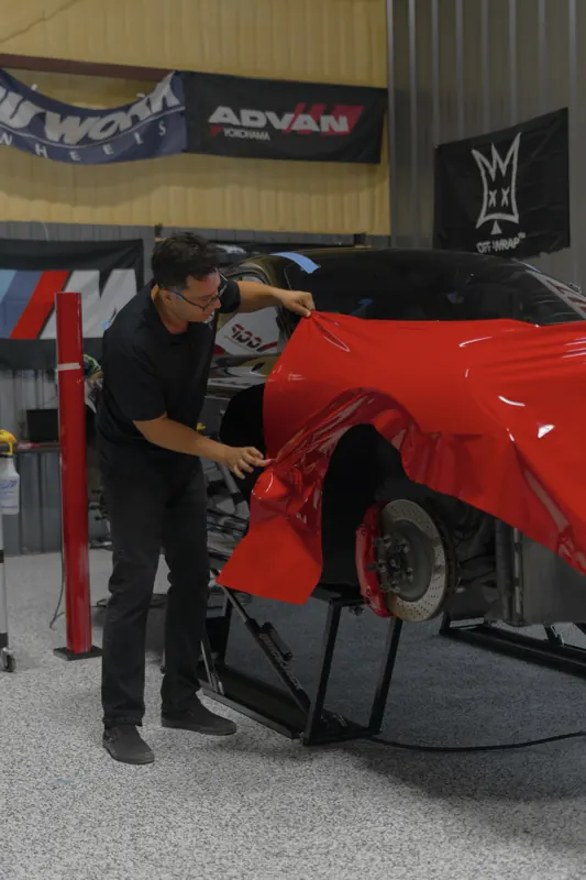 Alex laying red vinyl on a fender mid-install